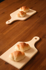 Two "rolls" on a cutting board x2 are placed on a wooden table