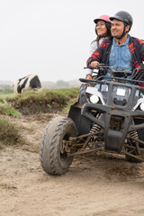 Vertical photo of a couple on a quad in a rural road