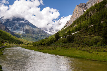 Fototapeta na wymiar River making a bend in Yading Nature Reserve. a famous landscape in Daocheng, Sichuan, China. Snow mountains, clouds in the sky