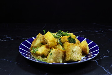 Traditional fried and stirred crispy tofu with soy sauce and pepper serving on the plate. Famous vegetarian food menu in Asia restaurant. 