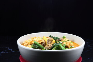 Traditional spicy hot vegetarian soup dressing with red curry serving in the bowl. Famous local menu in Asia restaurant.