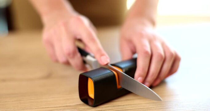 Woman sharpens knife with special knife sharpener closeup