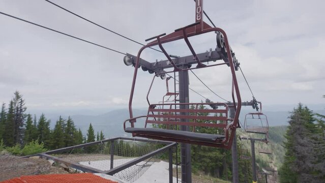 Slow motion two - seater chair lift swaying in breeze in summer at Idaho ski resort on overcast day