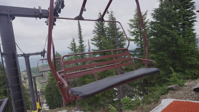 Red chairlift swaying in breeze in slow motion at summit of Idaho ski resort in summer time