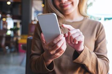 Closeup image of a young woman holding and using mobile phone