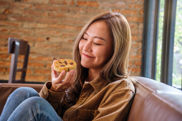 Portrait image of a beautiful young asian woman holding and eating a piece of cookie - Powered by Adobe