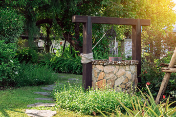 Beautiful artesian well made by stones and wheel pulley with metal bucket and rope in peaceful...