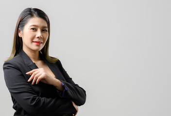 Smiling asian business woman pointing up and looking at the camera over gray background