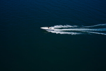 Luxurious Blue boat motorboat rushes through the waves of the blue Sea. Boat fast moving aerial view. Luxurious boat fast movement on dark water.
