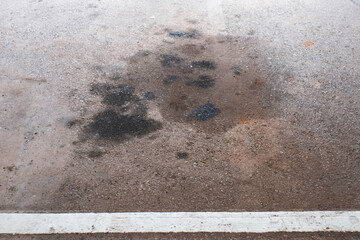 Oil stains on the floor of the parking garage that leaked from the engine of car.