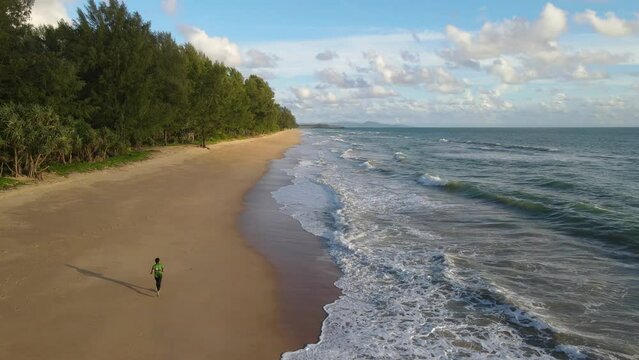 Aerial shot drone follow runer running on beach