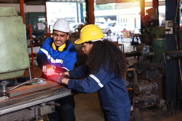 Young technician engineer or worker man in protective uniform had a hand accident on lathe machine in metal lathe factory. Safety colleague team helping him from accident. First aid training concept