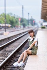 Portrait Young asian woman smiling tourist Traveler girl walking and with a holding the camera waits train travel journey is taken in railway platform Thailand, summer relax vacation Concept.