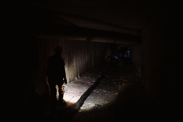 Obraz na płótnie Canvas Female digger with flashlight explores the tunnel