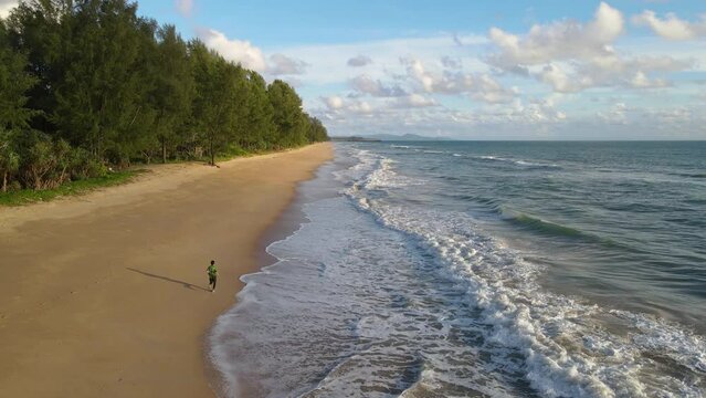 Aerial shot drone follow runer running on beach