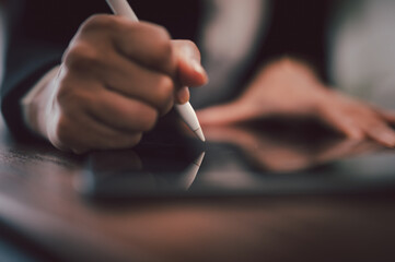 Business Woman using a digital pencil on iPad. hand holds stylus and puts an electronic signature...