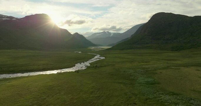 Rays of light shine on beautiful Jotunheimen National Park, fields of heater, peaceful river. Aerial, Drone. Norway.
