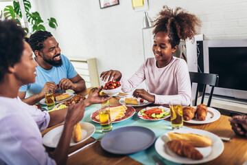 Fototapeta na wymiar A multi-generational African-American family enjoying food at their dinner table.