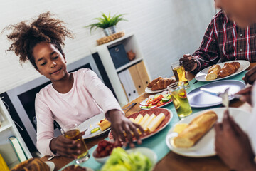 A multi-generational African-American family enjoying food at their dinner table.