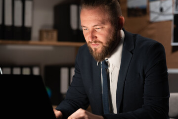 Detective processing evidence in office, working on computer