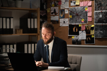 Detective working in office processing evidence using laptop.