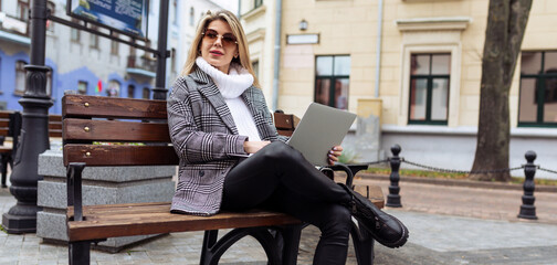 stylish business woman working on laptop online in the city