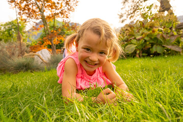 Little blond girl in backyard with pink shirt smiling into the camera