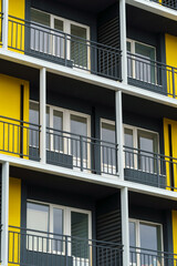 the facade of a modern multi-storey building, windows and balconies, yellow and black walls, the concept of urbanism and city construction