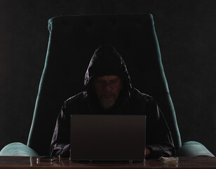 hooded hacker with laptop at night