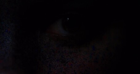 Eyes, art and creative with the eye of a woman opening and her face covered in different color paint. Beauty, artistic and eyes with a female in studio with light fading in and out for effect