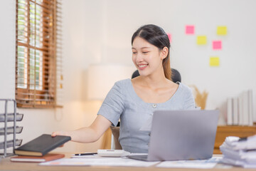 Young business Asian woman working at desk with laptop computer in home office, Tax Accountant Young Asian woman Doing Sales Invoice Accounting.
