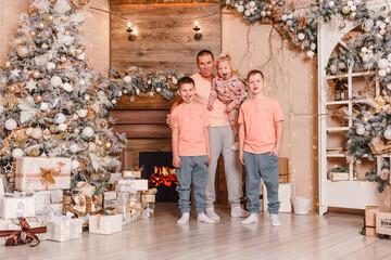 Fototapeta na wymiar happy father and three children near the Christmas tree. the same clothes. family photo shoot