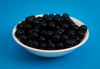 Bowl of Popping Boba Pearls on a Bright Blue Background