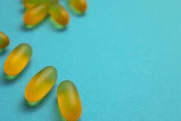 Capsules of fish fat oil, omega 3, vitamin e on the blue background with copy space. Healthcare,...