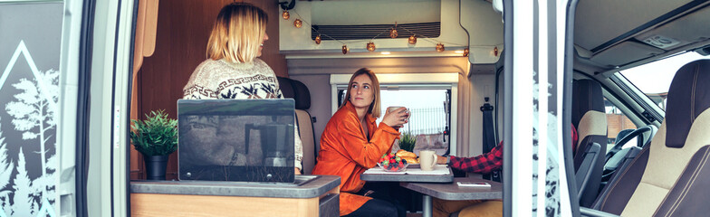 Happy friends having breakfast in a camper van in the morning
