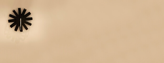 ベージュの壁に飾られたシンプルな時計