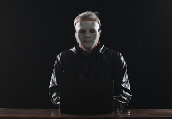 hacker in white mask with laptop