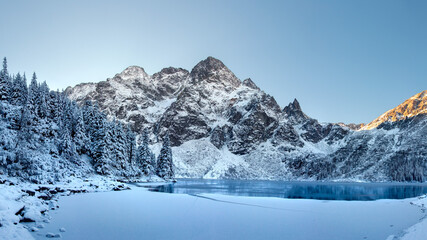 Winter landscape of frozen lake and covered snow trees in Tatra Mountains, Zakopane, Poland. Winter natural background. Beautiful winter sunrise in mountains.   - obrazy, fototapety, plakaty