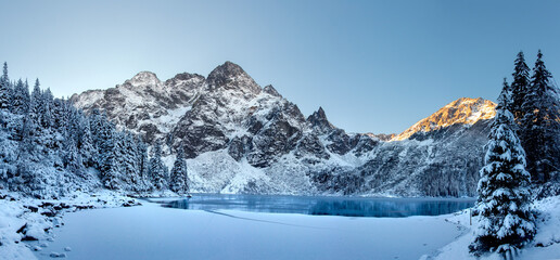 Winterlandschap van zonsopgang in Tatra-gebergte. Sneeuw bedekte sparren op bergen en bevroren meer. Prachtig uitzicht op het meer en de bergen.