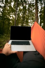 POV of a Tourist working remotely with Laptop Computer. Traveller Resting in a hammock in the...