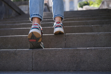 Closup of woman legs in sneakers walking up steps