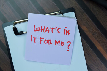 Concept of What's in it for me? write on sticky notes isolated on Wooden Table.