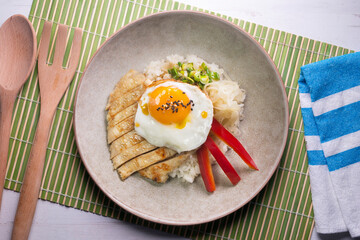 Teriyaki chicken donburi with fried egg, onion, red pepper and other vegetables. Typical Japanese dish.