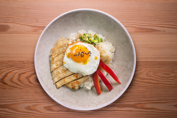 Teriyaki chicken donburi with fried egg, onion, red pepper and other vegetables. Typical Japanese dish.