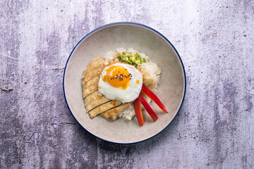 Teriyaki chicken donburi with fried egg, onion, red pepper and other vegetables. Typical Japanese dish.