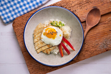 Teriyaki chicken donburi with fried egg, onion, red pepper and other vegetables. Typical Japanese dish.