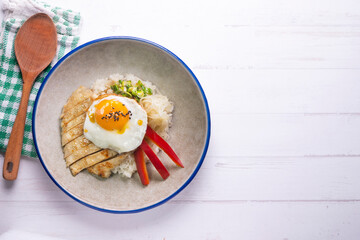 Teriyaki chicken donburi with fried egg, onion, red pepper and other vegetables. Typical Japanese dish.