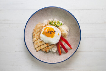 Teriyaki chicken donburi with fried egg, onion, red pepper and other vegetables. Typical Japanese dish.