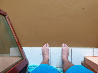 Bare feet at the front door of house overlooking brown muddy water after flooding hits the city, impact of natural disaster, in capital Dili, Timor Leste, Southeast Asia