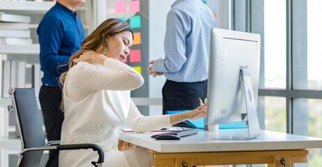 Millennial Asian successful professional female businesswoman in white formal suit sitting working in front computer screen monitor in company office room.